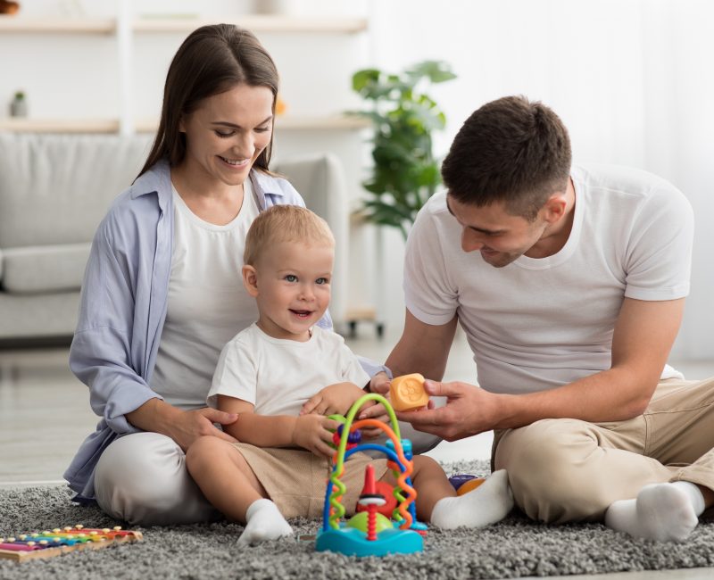Happy Parents And Adorable Infant Baby Playing With Development Toys At Home